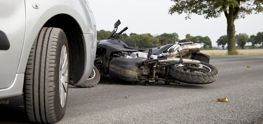 Moto tumbada en el asfalto tras una colisión con un coche en carretera