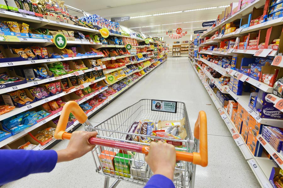 Cliente empujando un carrito por el pasillo de un supermercado, escenario habitual de caídas por suelo resbaladizo